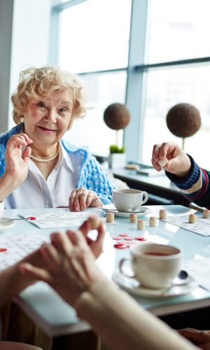 Happy senior man and women playing lotto and having tea