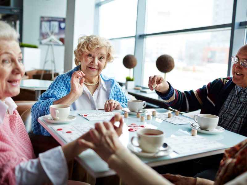 Happy senior man and women playing lotto and having tea